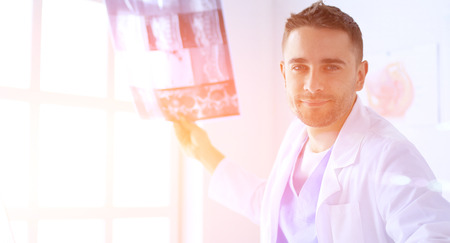 Handsome doctor is talking with young female patient and making notes while sitting in his office.の写真素材