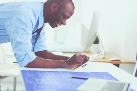 African american architect working with computer and blueprints in officeの写真素材