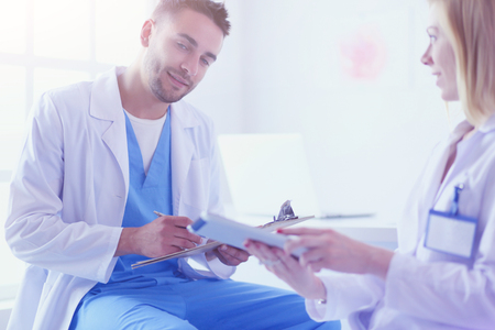 Handsome doctor is talking with young female doctor and making nの写真素材