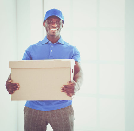 Portrait of an handsome happy deliverer with box