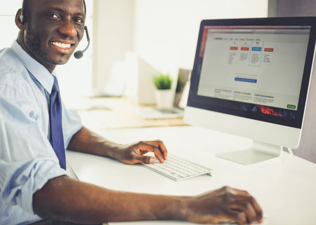 African american businessman on headset working on his laptop