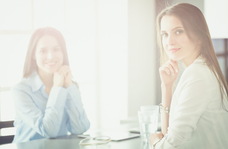 Two female colleagues in office sitting on the deskの写真素材