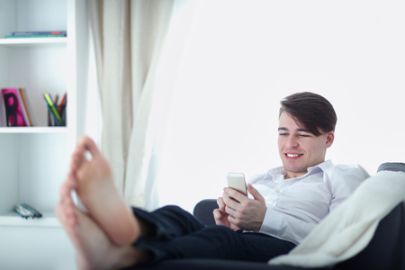 Handsome young man using smartphone at homeの写真素材