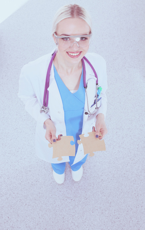 Woman doctor holding two connecting puzzle piecesの写真素材