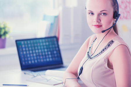 Beautiful business woman working at her desk with headset and laptopの写真素材