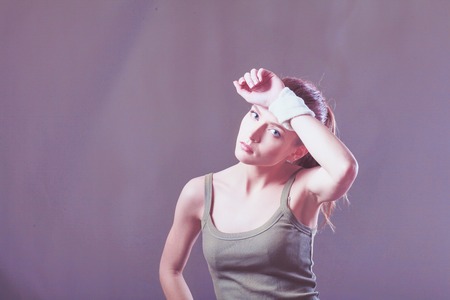 Tired sports woman sitting on exercises in fitness gymの写真素材