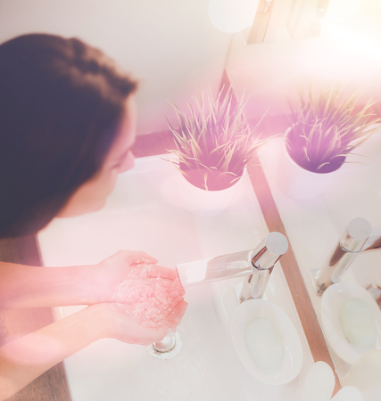 Young woman washing her face with clean water in bathroomの写真素材