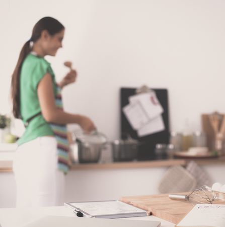 Smiling young woman in the kitchen, isolated on backgroundの写真素材