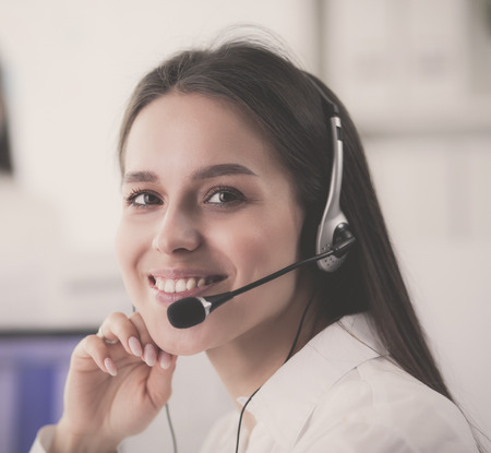 Smiling businesswoman or helpline operator with headset and computer at officeの写真素材