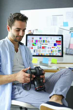 Portrait of young designer sitting at graphic studio in front of laptop and computer while working online.の写真素材