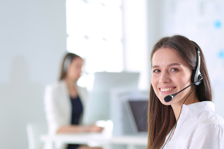 Smiling businesswoman or helpline operator with headset and computer at officeの写真素材
