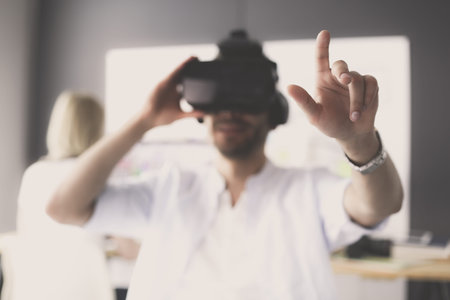 Young male software programmer testing a new app with 3d virtual reality glasses in office.