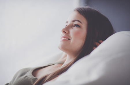 Pretty woman in her living room lying on the couch sending messの写真素材