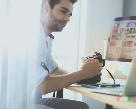 Portrait of young designer sitting at graphic studio in front of laptop and computer while working online.の写真素材
