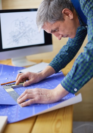 Architect working on drawing table in officeの写真素材
