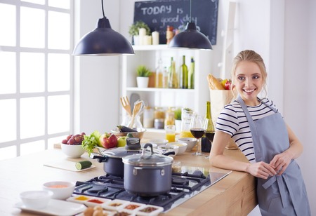 Beautiful young woman cooking in kitchen at homeの写真素材
