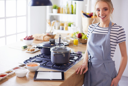Beautiful young woman cooking in kitchen at homeの写真素材