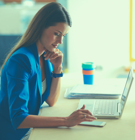 Woman sitting on the desk with laptopの写真素材