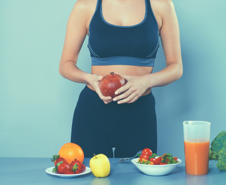 Young and beautiful woman standing near desk with vegetablesの写真素材