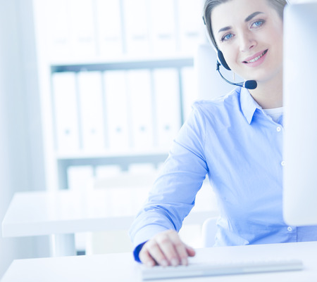 Serious pretty young woman working as support phone operator with headset in officeの写真素材