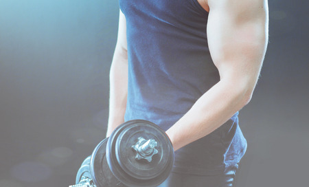 Handsome muscular man working out with dumbbellsの写真素材