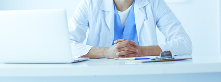 Portrait of a male doctor with laptop sitting at desk in medical officeの写真素材