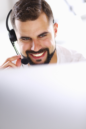 Portrait of a young man with a headset in front of a laptop computerの写真素材