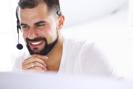 Portrait of a young man with a headset in front of a laptop computer