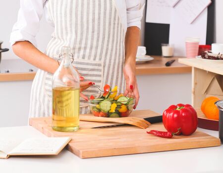 Young woman eating fresh salad in modern kitchenの写真素材