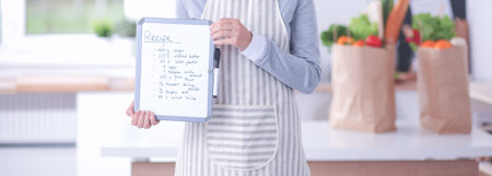 Young woman in the apron is cooking in the kitchen.