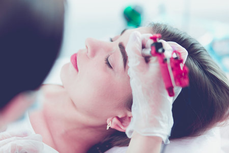 A young girl having red lips permanent makeup, micropigmentation