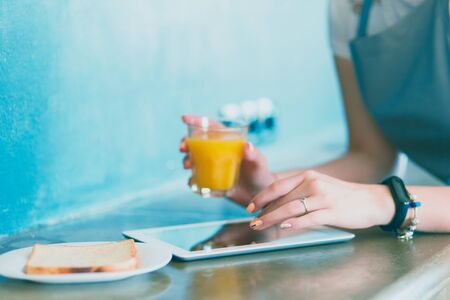 Attractive woman holding a glass of orange juice while standing in the kitchen.の写真素材