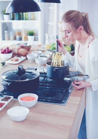 Beautiful young woman cooking in kitchen at homeの写真素材