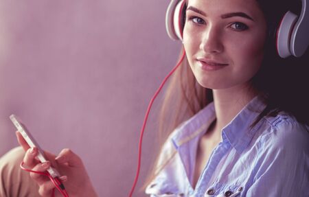 Young happy girl sitting on floor and listening musicの写真素材