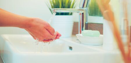 Young woman washing her face with clean water in bathroomの写真素材
