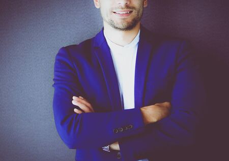 Young business man standing isolated on grey backgroundの写真素材