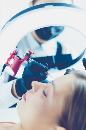 Microblading eyebrows work flow in a beauty salon. Woman having her eye brows tintedの写真素材