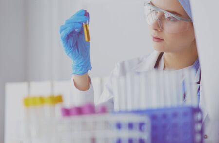 A female medical or scientific researcher or woman doctor looking at a test tube of clear solution in a laboratoryの写真素材