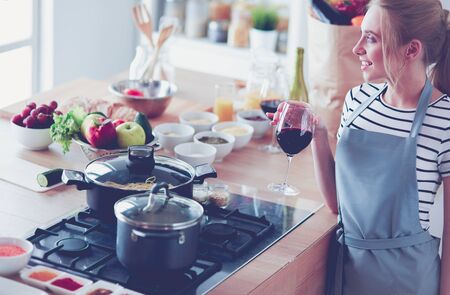 Pretty woman drinking some wine at home in kitchenの写真素材