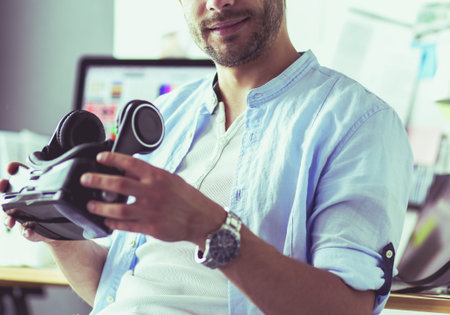 Young male software programmer testing a new app with 3d virtual reality glasses in office.