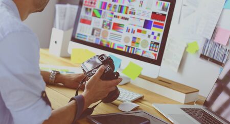 Portrait of young designer sitting at graphic studio in front of laptop and computer while working onlineの写真素材