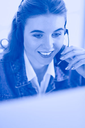 Portrait of beautiful business woman working at her desk with headset and laptop