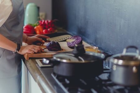 Young woman cutting vegetables in kitchen standing near desk.の写真素材