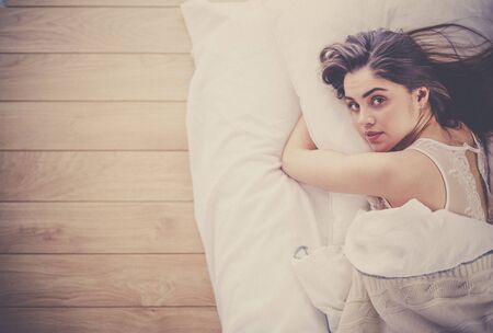 Pretty woman lying down on her bed at homeの写真素材
