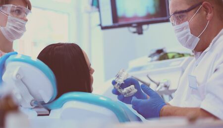 Male dentists examining and working on young female patient.の写真素材