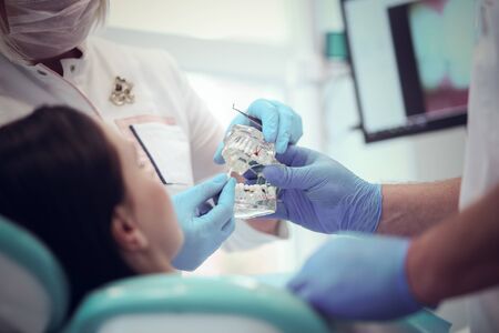 Senior male dentist in dental office talking with female patient and preparing for treatment.の写真素材