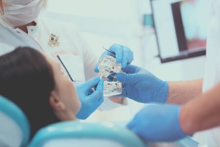 Senior male dentist in dental office talking with female patient and preparing for treatment.の写真素材