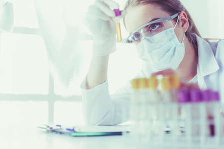 Portrait of pretty female laboratory assistant analyzing a blood sample at hospitalの写真素材