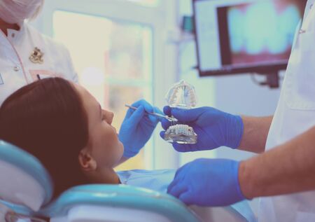 Senior male dentist in dental office talking with female patient and preparing for treatment.の写真素材