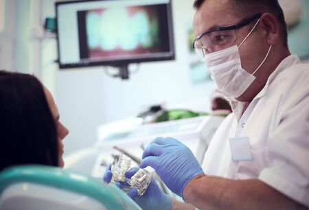 Male dentists examining and working on young female patient.Dentist's officeの写真素材